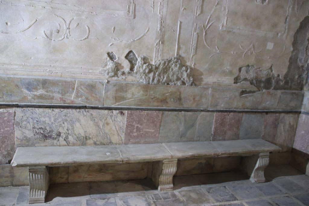 Suburban Baths, Herculaneum, October 2025. Tepidarium west wall.
The zoccolo on the walls of the tepidarium was formed from slabs of marble.
A bench was set against all three walls; this one has three supports against the west wall.
Photo courtesy of Klaus Heese.